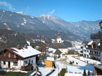 a town in the snow with a church and mountains at Apartment Poldi by Interhome in Haus im Ennstal