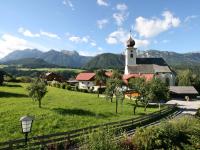a church in a field with mountains in the background at Apartment Poldi by Interhome in Haus im Ennstal