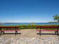 two red benches sitting next to the ocean at Apartment Berasteguia-5 by Interhome in Ciboure