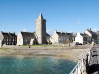 an old building with a tower next to a body of water at Holiday Home La Plage by Interhome in Denneville