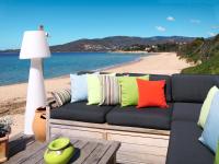 a couch with colorful pillows sitting on a beach at Holiday Home La Pinede - SAG171 by Interhome in Sagone