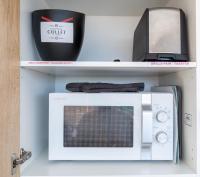 a white microwave on a shelf with a box at La Perle du Cap in Case-Pilote