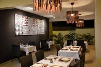 Un restaurante con mesas y sillas blancas y candelabros. en Gasaro Hotel, en Mtwapa