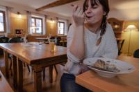 una mujer sentada en una mesa comiendo un plato de comida en Kastanienhof Pfettrach, en Altdorf