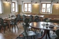 Un comedor con mesas y sillas y ventanas. en Kastanienhof Pfettrach, en Altdorf