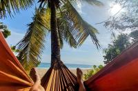 a person laying in a hammock looking at the beach at Studio &quot;Prestige&quot; Sainte Luce in Sainte-Luce