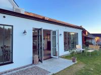 Una casa blanca con puertas corredizas y un patio. en Ekenäs Gård på Österlen, en Kivik