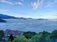 a house on a hill above a sea of clouds at Ming Ging Farm in Ren&#39;ai
