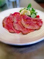 Un trozo de carne en un plato blanco con ensalada. en HOTEL RISTORANTE DELLE VALLI, en Germagnano