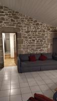 a living room with a couch and a stone wall at Gite la Péraie - Le Roseau in Treize-Vents
