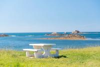 a white bench sitting on top of a field with the ocean at Villa Saint Kirio - piscine et spa in Morlaix