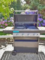 a barbecue grill in front of a bench with flowers at Villa Saint Kirio - piscine et spa in Morlaix
