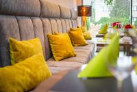 a row of couches with yellow pillows in a restaurant at Novotel Poznań Malta in Poznań