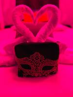 a black mask and two pink hearts on a bed at Suite Cupidon- Domaine des trois châteaux in Moisenay