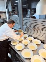 un homme préparant à manger dans une cuisine avec des assiettes blanches dans l'établissement FORESTERIA DEL GAVI, à  Tassarolo
