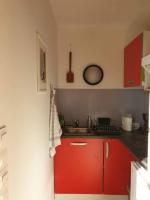 a small kitchen with red cabinets and a sink at Le Nid des Anges, votre studio à la campagne. in Saint-Laurent-du-Plan
