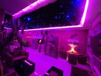 una habitación con luces moradas, sillas y un escenario en Patto S Apa باتو للشقق المخدومة, en Al Bahah