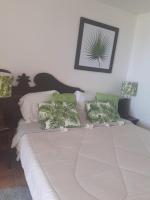 a bed with green and white pillows on it at Pierre et Vacances Vue Mer in Sainte-Luce