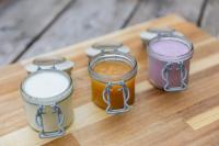 Un grupo de cuatro frascos en una tabla de cortar de madera. en Hiša Ojstrica, en Solčava