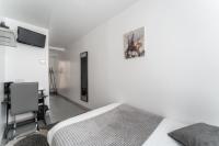 a white bedroom with a bed and a desk and a television at L&#39;Oasis Montparnasse in Paris