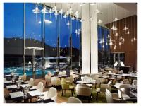 Um restaurante com mesas e cadeiras e uma grande janela. em OliveBay Hotel em Saikai