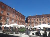 a courtyard with tables and umbrellas in front of buildings at Pause COCOONING en Centre historique in Montauban