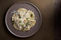 Un plato de ravioles con queso sobre una mesa. en fink Restaurant & Suites, en Brixen