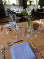 a wooden table with wine glasses and a vase with flowers at Nybro Stora Hotellet in Nybro