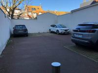 two cars parked in a parking lot next to a white wall at Mayfair in Le Touquet-Paris-Plage