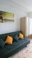 a green couch with two yellow pillows in a room at Au Coeur du Jura, Logement au calme in Champagnole