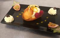 a black plate with a dessert with fruit and whipped cream at Logis Hotel Restaurant de La Madeleine in Commercy