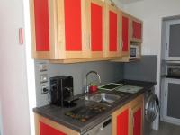 a small kitchen with red cabinets and a sink at Appartement Sète, 2 pièces, 4 personnes - FR-1-338-136 in Sète