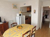 a kitchen with a table and a white refrigerator at Appartement Royan, 2 pièces, 4 personnes - FR-1-71-62 in Royan