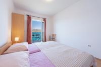 a bedroom with a large bed with a view of the ocean at Apartmani Ivušić in Dubrava
