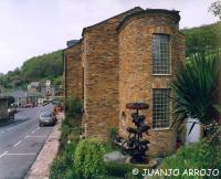 Un edificio de ladrillo con un bebedero para pájaros en frente. en HOTEL RURAL OSCOS, en Villanueva de Oscos