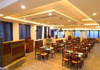 uma sala de jantar com mesas, cadeiras e janelas em Lazo Eucy Paradise ,Kodaikanal em Kodaikānāl