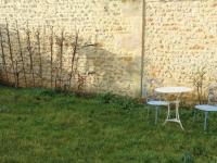 two chairs and a table in the grass next to a wall at Maison Fouras, 6 pièces, 8 personnes - FR-1-709-39 in Fouras