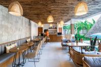 un ristorante con soffitti in legno, tavoli e sedie di Roomates Hostel Canggu by Ini Vie Hospitality a Canggu
