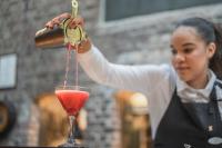 una mujer sirviendo una bebida roja en un vaso en GamlaVærket Gjæstgiveri og Tracteringssted, en Sandnes