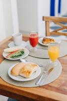 a table with plates of food and glasses of orange juice at Pousada Villa Santô in Guarujá