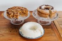 four different cakes on plates on a wooden table at Pousada Villa Santô in Guarujá