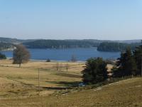 a large field with a lake in the background at La ch&#39;tiote meizou in Mazet-Saint-Voy