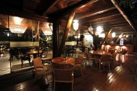 Un restaurante con mesas y sillas de madera y luces. en Pousada Triboju, en Fernando de Noronha