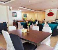 una sala da pranzo con un tavolo e sedie bianche di Pratama Hotel & Convention Mataram a Mataram