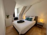 a bedroom with a large white bed with green pillows at Le Briais in Melun