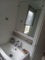 a white bathroom with a sink and a mirror at Mobilhome 6 pers avec Clim in Saint-Georges-de-Didonne