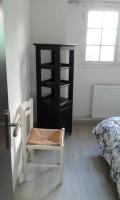 a bedroom with a chair and a black book shelf at appartement au rez de jardin in Morangis
