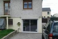 a car parked in front of a house with a sliding door at appartement au rez de jardin in Morangis