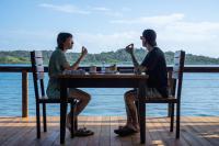 a man and woman sitting at a table by the water at Roam Yoga & Wellness Lodge in Bocas del Toro