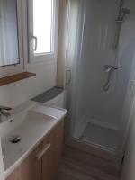 a white bathroom with a shower and a sink at MH 4 personnes 5 étoiles plages du debarquement in Sainte-Mère-Église